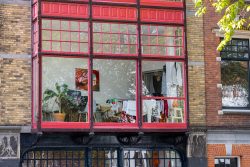 Amsterdam und Umgebung April 2025 Blick auf eine Wohnung mit Pflanzen und Wäsche hinter einer roten Fensterfront Amsterdam und Umgebung April 2025 Große Fensterfront mit Pflanzen und Wäsche in einem Gebäude