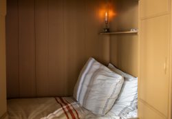 Amsterdam und Umgebung April 2025 Ein kleines Schlafzimmer mit Kerze beleuchtet, ideal zum Entspannen Amsterdam und Umgebung April 2025 Gemütliches Schlafzimmer mit Kerzenlicht und gestreifter Decke