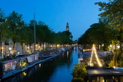 Amsterdam und Umgebung April 2025 Ein idyllischer Abendblick auf einen der berühmten Kanäle Amsterdams Amsterdam und Umgebung April 2025 Malersche Abendansicht eines Amsterdamer Kanals mit Häusern und Bäumen im Hintergrund