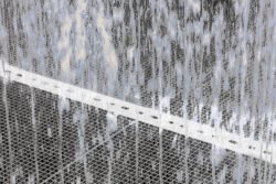 Amsterdam und Umgebung April 2025 Wasserbewegung über einem kunstvoll gestalteten Metallgitter. Amsterdam und Umgebung April 2025 Wasser fließt über Metallgitter in einem modernen Brunnen