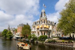 Amsterdam und Umgebung April 2025 Ein schönes Beispiel historischer Architektur in Amsterdam mit einem vorbeifahrenden Boot. Amsterdam und Umgebung April 2025 Historisches Gebäude am Kanal in Amsterdam mit Boot im Vordergrund