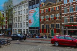 Amsterdam und Umgebung April 2025 Straßenszene in Amsterdam mit einem Plakat für eine Rembrandt-Ausstellung im Hintergrund Amsterdam und Umgebung April 2025 Straßenszene in Amsterdam mit historischen Gebäuden und Werbeplakat für Rembrandt-Ausstellung
