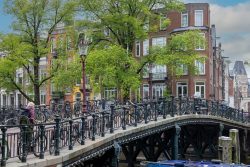 Amsterdam und Umgebung April 2025 Eine malerische Brücke in Amsterdam, umgeben von Fahrrädern und typischen Backsteinhäusern der Stadt Amsterdam und Umgebung April 2025 Historische Brücke in Amsterdam mit Fahrrädern und Backsteinhäusern
