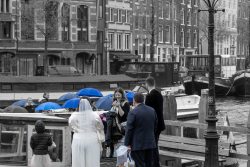 Amsterdam und Umgebung April 2025 Das Brautpaar und Gäste genießen den schönen Tag am Kanal in Amsterdam Amsterdam und Umgebung April 2025 Hochzeitspaar und Gäste an einem Kanal vor historischer Kulisse in Amsterdam