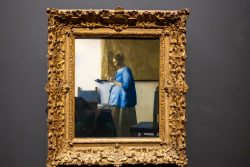 Amsterdam und Umgebung April 2025 Ein Meisterwerk von Jan Vermeer, das eine konzentrierte Frau in blauem Kleid zeigt Amsterdam und Umgebung April 2025 Gemälde einer Frau in blauem Kleid von Jan Vermeer im goldenen Rahmen