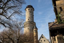 Bamberg - Bamberg Weihnachtsmarkt 2023 Ein beeindruckender mittelalterlicher Turm ragt neben malerischen Fachwerkgebäuden in den blauen Himmel. Bamberg - Bamberg Weihnachtsmarkt 2023 Mittelalterlicher Steinturm und Fachwerkhäuser in sonniger Landschaft