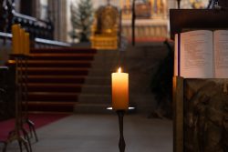 Bamberg - Bamberg Weihnachtsmarkt 2023 Eine einsame Kerze leuchtet in der ruhigen Atmosphäre einer Kirche. Bamberg - Bamberg Weihnachtsmarkt 2023 Kerze in einer Kirche mit rotem Teppich und beleuchtetem Podest