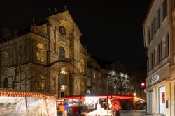Bamberg - Bamberg Weihnachtsmarkt 2023 Ein lebendiger Nachtmarkt vor einer prächtigen Kirche erhellt die Nacht Bamberg - Bamberg Weihnachtsmarkt 2023 Nachtmarkt vor beleuchteter Kirche in einer deutschen Stadt