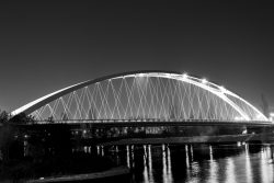 Fotografie von Aloys Peter Trenz Die nächtliche Beleuchtung betont die Architektur dieser beeindruckenden Brücke Ausgewählte Fotomotive von Aloys Peter Trenz Fotografie von Aloys Peter Trenz Schwarz-Weiß-Foto einer modernen Bogenbrücke bei Nacht mit Lichtern, die im Wasser reflektieren Ausgewählte Fotomotive von Aloys Peter Trenz