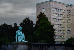 Frankfurt IG Farbengebaeude Goethe Universitaet Bronzestatue einer sitzenden Figur vor einem modernen Steingebäude in einer urbanen Umgebung
