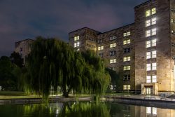 Frankfurt IG Farbengebaeude Goethe Universitaet Abendaufnahme eines beleuchteten Bürogebäudes mit Teich und Trauerweide
