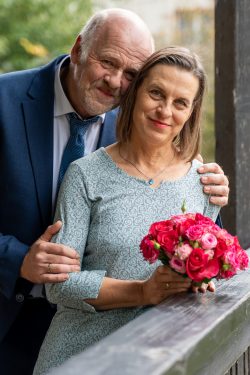 Hochzeitsfotografie Älteres Paar lächelt bei Hochzeit mit Blumenstrauß