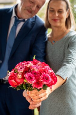 Hochzeitsfotografie Älteres Paar mit Blumenstrauß aus rosa Rosen posiert zusammen