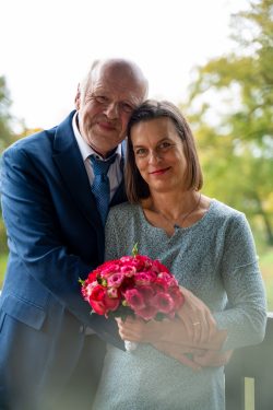 Hochzeitsfotografie Älteres Paar umarmt sich mit Blumenstrauß im Freien