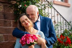 Hochzeitsfotografie Älteres Paar mit Blumenstrauß vor romantischem Hintergrund