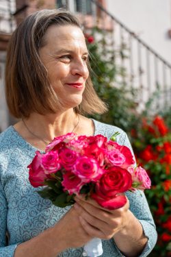 Hochzeitsfotografie Ältere Frau mit Blumenstrauß, lächelnd im Garten