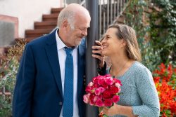 Hochzeitsfotografie Älteres Paar lächelt einander an mit Blumenstrauß