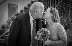 Hochzeitsfotografie Älteres Paar teilt einen Kuss bei einer Hochzeit im Freien