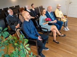 Hochzeitsfotografie Zwei Menschen sitzen in einem Trauzimmer umgeben von Familie und Freunden