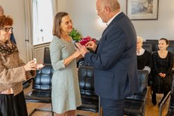 Hochzeitsfotografie Zeremonie: Mann steckt Frau Ring an. Menschen schauen zu