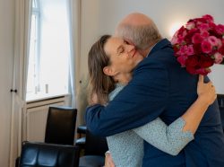 Hochzeitsfotografie Älteres Paar umarmt sich herzlich mit einem Blumenstrauß