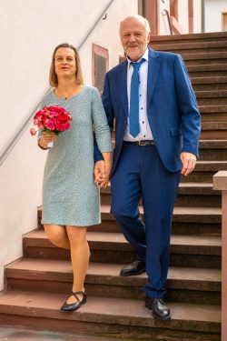 Hochzeitsfotografie Elegantes Paar im blauen Anzug und Kleid auf Treppe mit Blumenstrauß