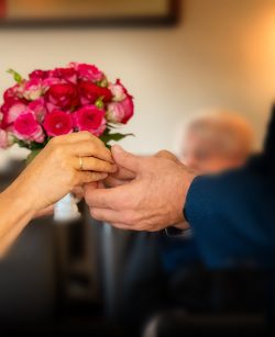 Hochzeitsfotografie Nahaufnahme von zwei Händen, die sich bei einer Hochzeit Blumen reichen