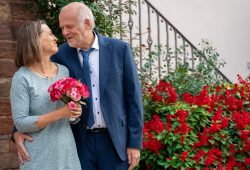 Hochzeitsfotografie Älteres Paar in Hochzeitskleidung mit Blumenstrauß im Garten