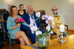 Hochzeitsfotografie Hochzeitsteilnehmer in fröhlicher Stimmung mit Brautstrauß und Orchideen.