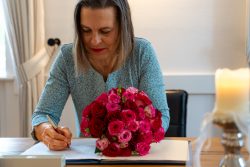 Hochzeitsfotografie Frau unterschreibt Dokument neben Blumenstrauß auf Holztisch