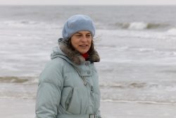 Insel Sylt Februar 2025 Eine Frau genießt einen ruhigen Tag am Strand, bekleidet mit warmer Kleidung Insel Sylt Februar 2025 Frau in blauer Jacke und Mütze am Strand bei kühlem Wetter
