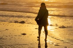 Insel Sylt Februar 2025 Ein ruhiger Moment am Meer beim Sonnenuntergang Insel Sylt Februar 2025 Person spaziert bei Sonnenuntergang am Strand entlang