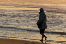Insel Sylt Februar 2025 Eine Person genießt einen ruhigen Spaziergang am Strand während des Sonnenuntergangs Insel Sylt Februar 2025 Person spaziert barfuß am Strand bei Sonnenuntergang