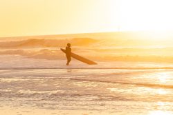 Insel Sylt Februar 2025 Ein Surfer genießt den Sonnenuntergang am Strand Insel Sylt Februar 2025 Surfer am sonnigen Strand bei Sonnenuntergang mit Surfbrett