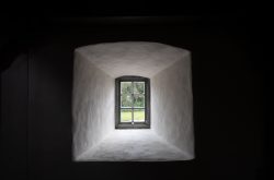 Insel Sylt Februar 2025 Ein einfaches, einzelnes Fenster, das aus der Dunkelheit ins Freie schaut Insel Sylt Februar 2025 Einzelnes Fenster in einem dunklen Raum mit Blick ins Grüne