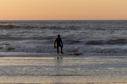 Insel Sylt Februar 2025 Ein Surfer betritt bei Sonnenuntergang das ruhige Meer Insel Sylt Februar 2025 Surfer geht bei Sonnenuntergang ins Meer