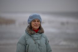 Insel Sylt Februar 2025 Eine Frau genießt einen windigen Tag am Strand Insel Sylt Februar 2025 Frau in blauer Jacke und Mütze am stürmischen Strand