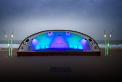 Insel Sylt Februar 2025 Eine muschelförmige Bühne an der Küste, beleuchtet in Blau und Grün Insel Sylt Februar 2025 Beleuchtete Küstenbühne in Muschelform bei Nacht