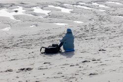 Insel Sylt Februar 2025 Eine Person genießt die Ruhe am schneebedeckten Strand Insel Sylt Februar 2025 Person in Winterkleidung sitzt allein am verschneiten Strand