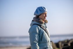 Insel Sylt Februar 2025 Eine Frau genießt einen Spaziergang am Strand an einem klaren Tag. Insel Sylt Februar 2025 Frau in blauem Mantel und Baskenmütze am Strand