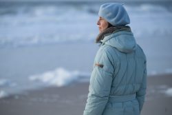 Insel Sylt Februar 2025 Eine Frau genießt den Blick aufs winterliche Meer Insel Sylt Februar 2025 Frau im Wintermantel am verschneiten Strand mit Blick aufs Meer