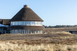 Insel Sylt Februar 2025 Ein traditionelles Reetdachhaus steht inmitten einer offenen Landschaft Insel Sylt Februar 2025 Traditionelles Reetdachhaus auf einem weitläufigen, grasbewachsenen Feld