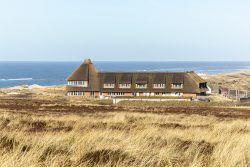 Insel Sylt Februar 2025 Ein traditionelles Haus mit Reetdach liegt malerisch an der Nordseeküste Insel Sylt Februar 2025 Historisches Reetdachhaus an Nordseeküste umgeben von Dünen