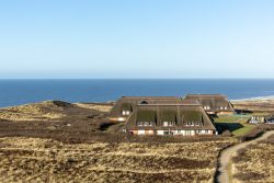 Insel Sylt Februar 2025 Traditionelle Reetdachhäuser mit Blick auf die Nordsee, umgeben von Dünen und Küstenlandschaft Insel Sylt Februar 2025 Reetdachhäuser auf Sylt mit Meerblick im Hintergrund