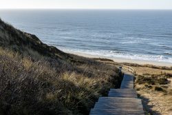 Insel Sylt Februar 2025 Ein malerischer Holzweg zur Nordsee an einem ruhigen Strand. Insel Sylt Februar 2025 Holzweg führt zu einem ruhigen Strand mit Blick auf das Meer an der Nordsee