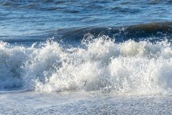 Insel Sylt Februar 2025 Schaumige Wellen brechen sanft an einem sonnigen Strand Insel Sylt Februar 2025 Wellen brechen am Sandstrand eines Ozeans