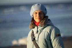 Insel Sylt Februar 2025 Eine Frau genießt einen sonnigen Tag am Strand im Winter Insel Sylt Februar 2025 Frau in blauer Winterjacke und Mütze am Strand