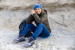Insel Sylt und Hallig Hooge Oktober 2025 Eine Frau genießt einen ruhigen Tag am Strand, während sie auf dem Sand sitzt Insel Sylt und Hallig Hooge Oktober 2025 Frau in blauer Mütze sitzt entspannt am Strand