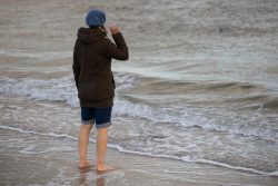 Insel Sylt und Hallig Hooge Oktober 2025 Eine Frau genießt den ruhigen Moment am Meer Insel Sylt und Hallig Hooge Oktober 2025 Frau mit Mütze steht barfuß am Strand, blickt aufs Meer
