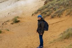 Insel Sylt und Hallig Hooge Oktober 2025 Eine Person in Winterkleidung genießt eine Wanderung auf einer sandigen Düne Insel Sylt und Hallig Hooge Oktober 2025 Person wandert auf sandiger Düne in winterlicher Kleidung